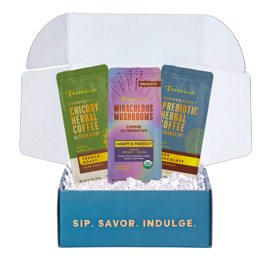 Open Teeccino gift box with French Roast Chicory Herbal Coffee, Miraculous Mushrooms Coffee Alternative and Prebiotic SuperBoost Dark Chocolate Herbal Coffee in white crinkle paper; teal box reads Sip. Savor. Indulge. [BU001-hero-20261022]