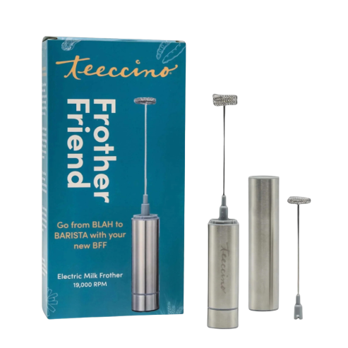 A Teeccino Frother Friend electric milk frother is shown with its teal product box and separated components on a transparent background. The stainless steel handheld frother includes a whisk attachment, motor body, battery tube, and end cap. The packaging highlights its compact design and 19,000 RPM power for creating smooth, creamy foam for beverages at home.