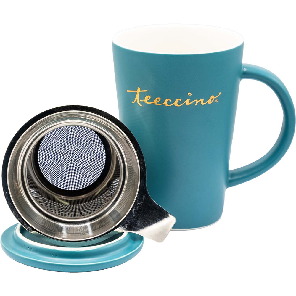 A matte teal ceramic mug with a matching lid and a side handle. The "Teeccino" brand name is printed horizontally in gold script on the front. A silver metal tea infuser tab extends from beneath the lid. The mug is centered against a solid white background, showing its tapered cylindrical shape and smooth finish.