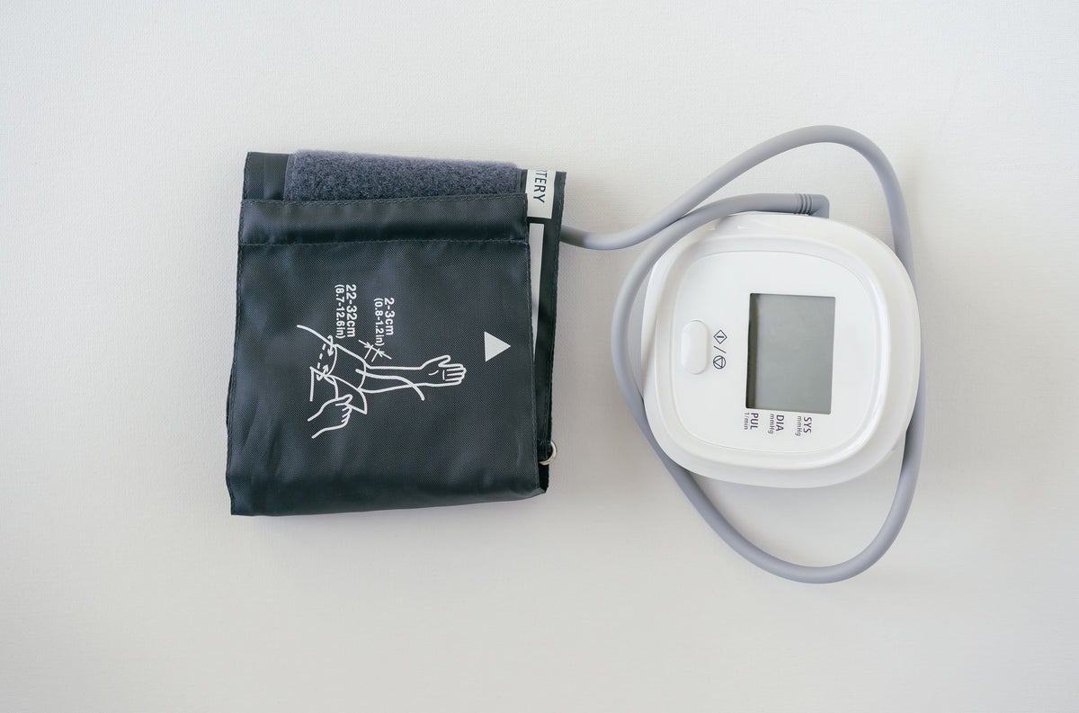Digital blood pressure monitor and arm cuff on a white background